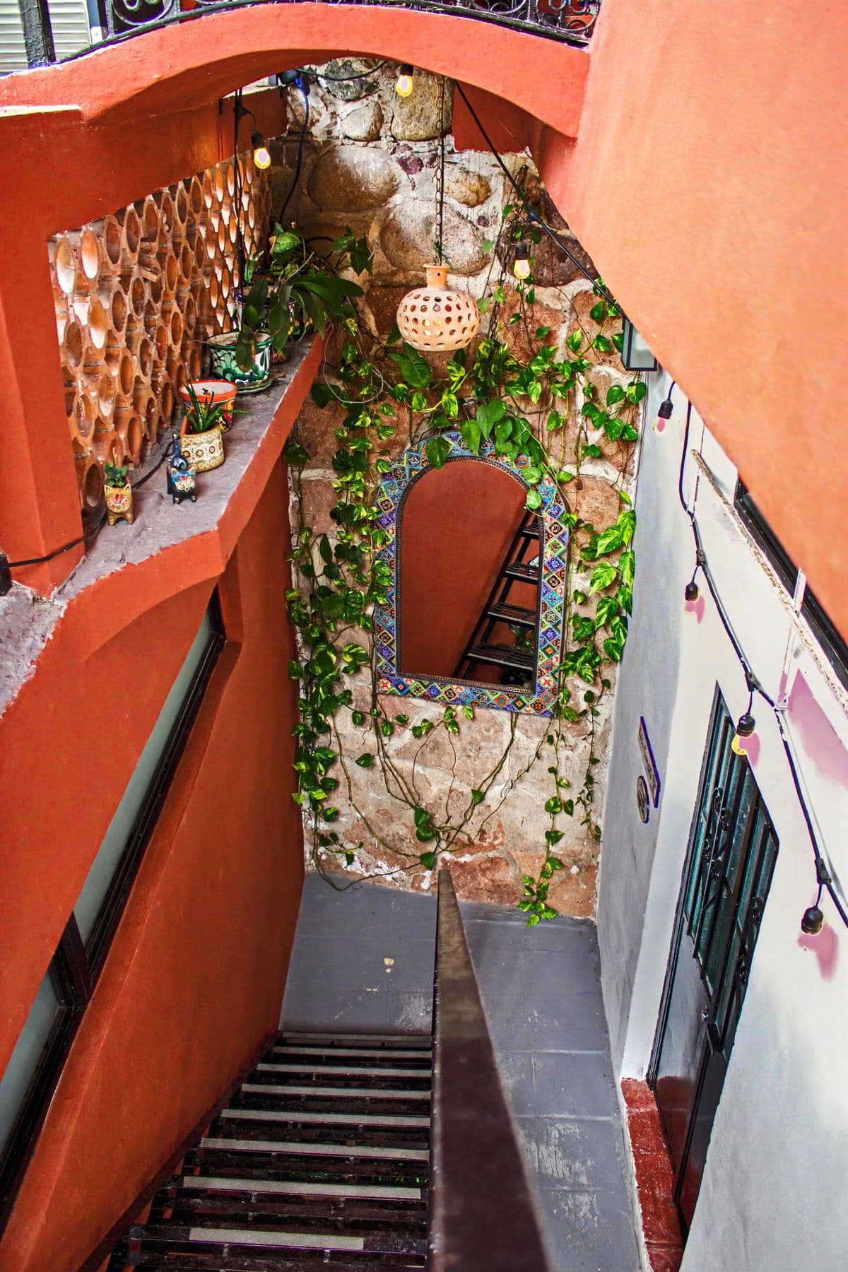 The tiled entry stairwell at Villa Amistad, with a talavera niche and vines on the stone wall