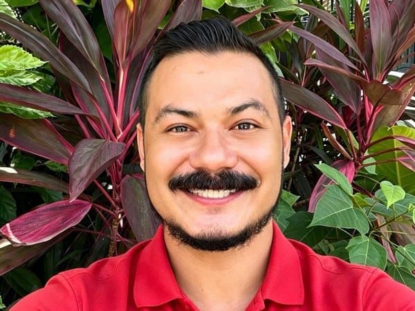 Carlos, quien da las clases privadas de español, sonriendo en un jardín