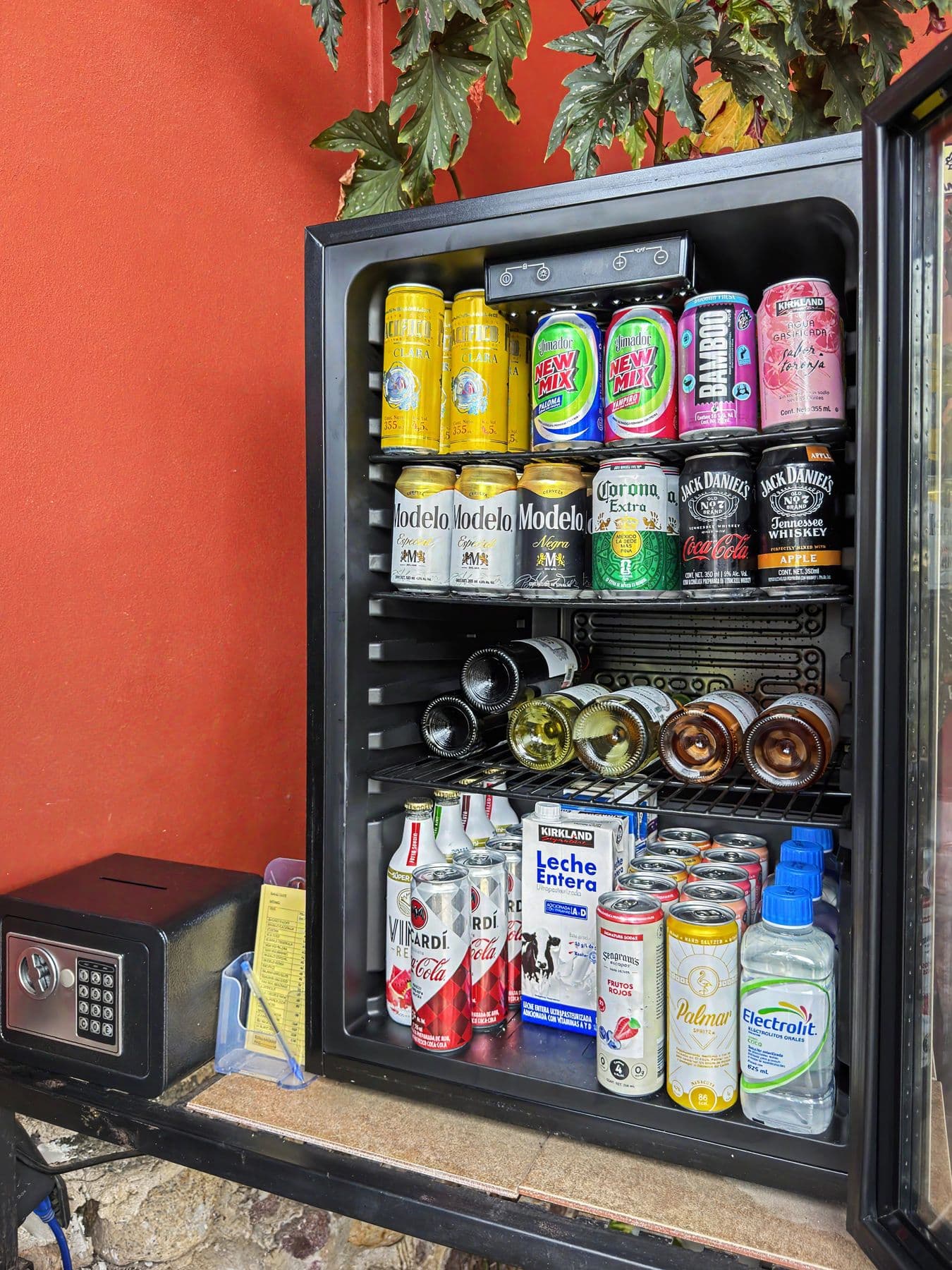 El refrigerador del Honor Bar con cerveza fría y vino, contra un muro de terracota