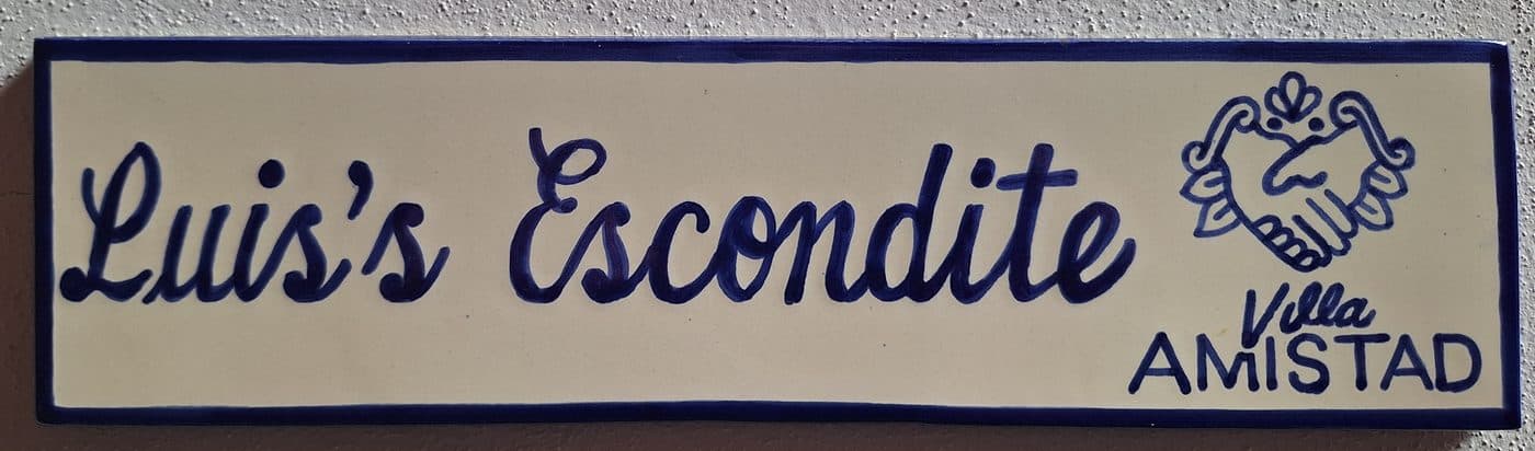 The hand-painted sign reading Luis's Escondite beside the office door at Villa Amistad